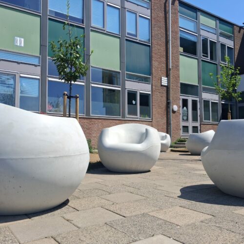 Betonnen zitelementen en tafel Stool 40 Witte betonnen zitelementen uit de Stool lijn geplaatst op een plein in Gouda